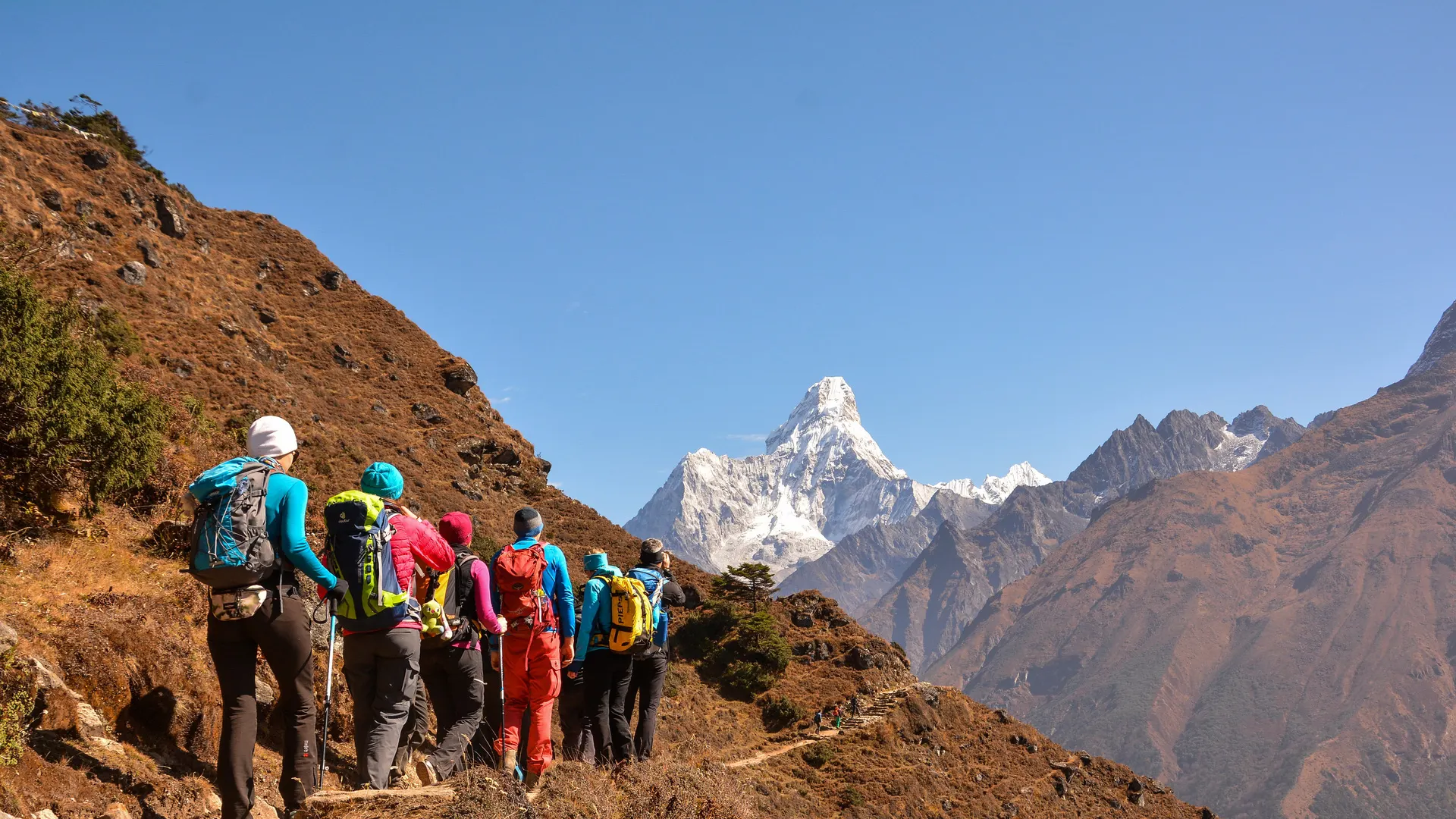 Trekkers walking a dry trail below the peak of Ama Dablam in the Khumbu