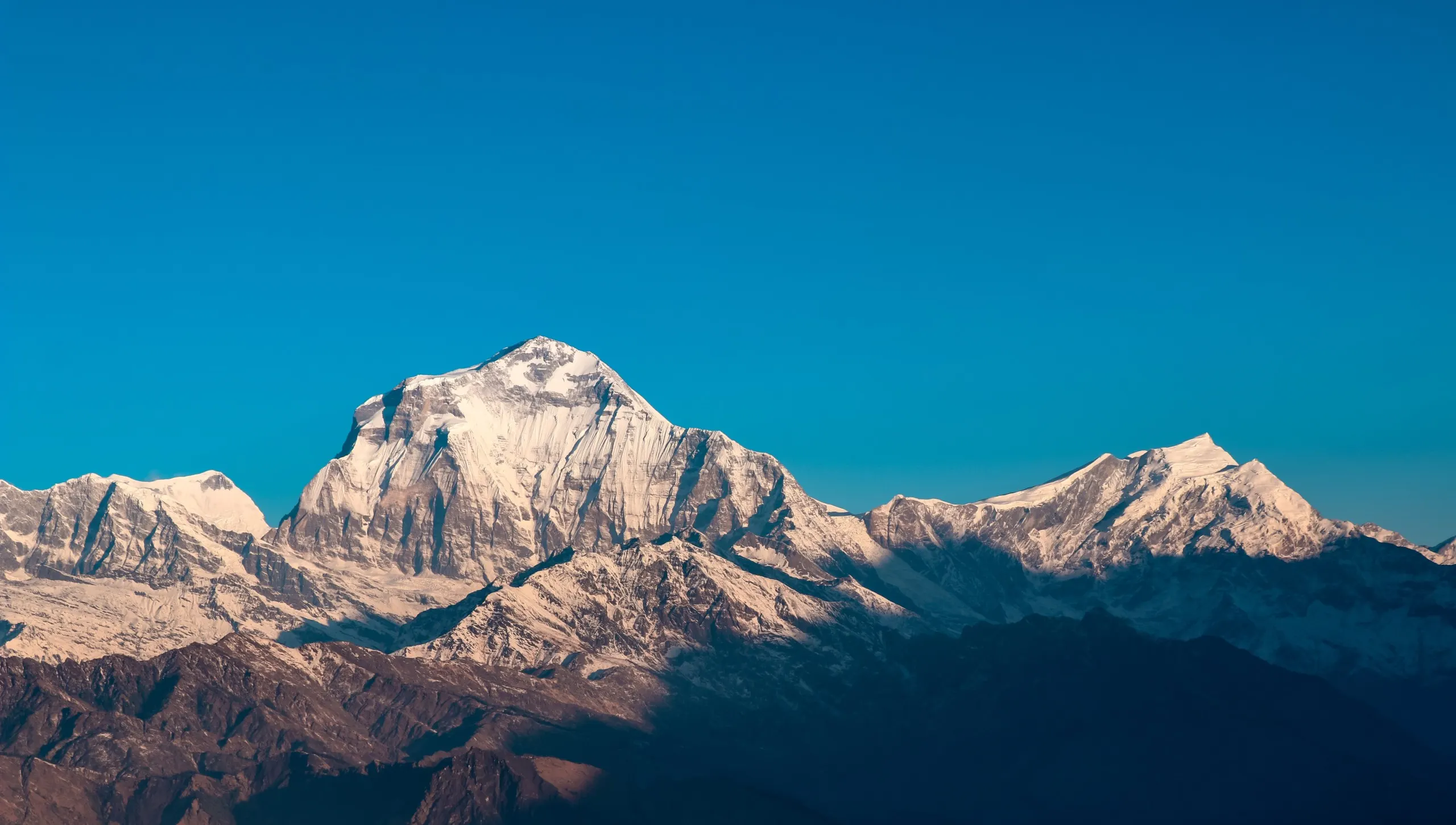 The snow ridge of Dhaulagiri under a deep blue sky, seen across the Kali Gandaki