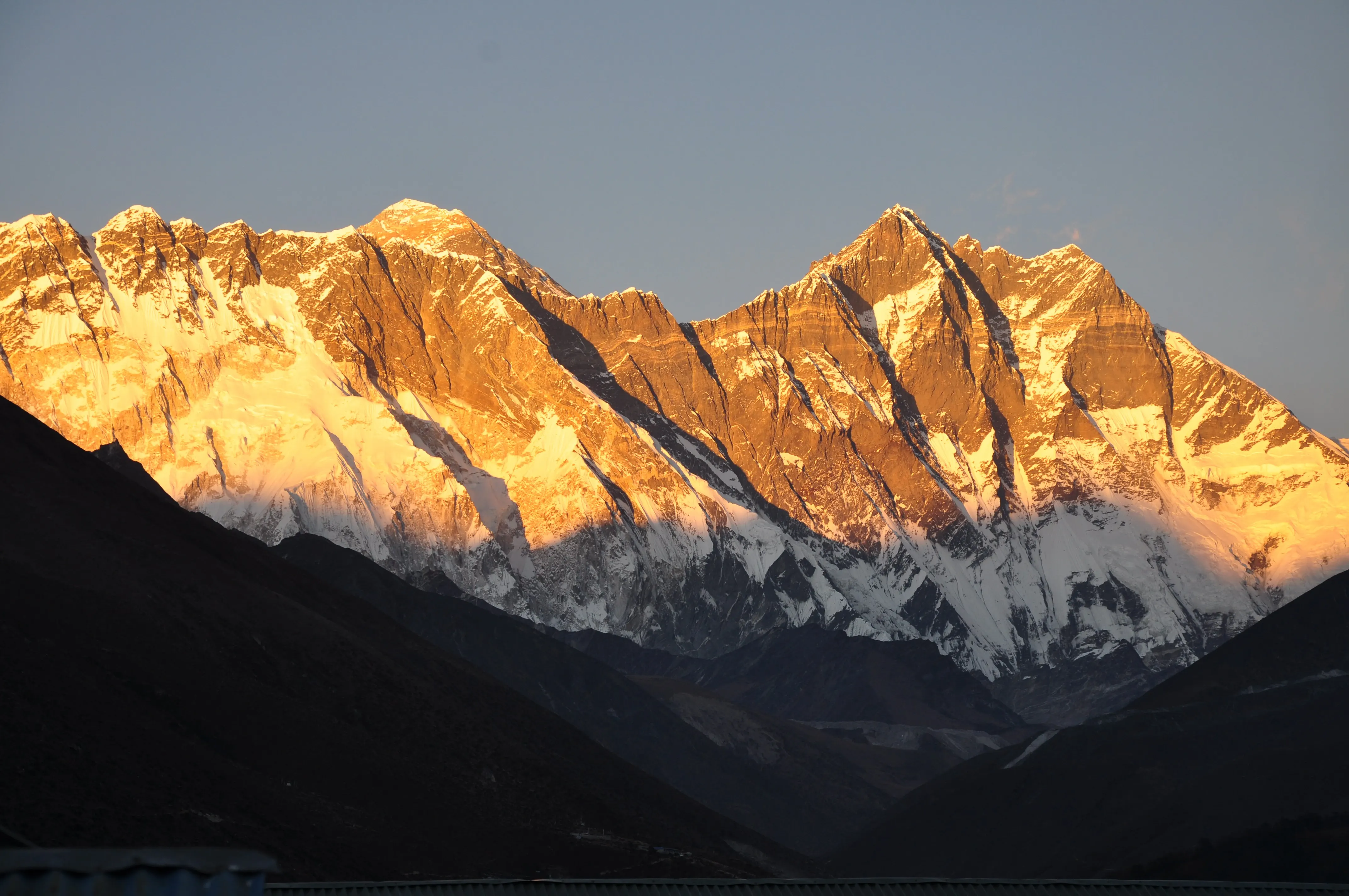 The Nuptse–Lhotse wall and the summit of Everest lit orange by sunset above a shadowed valley